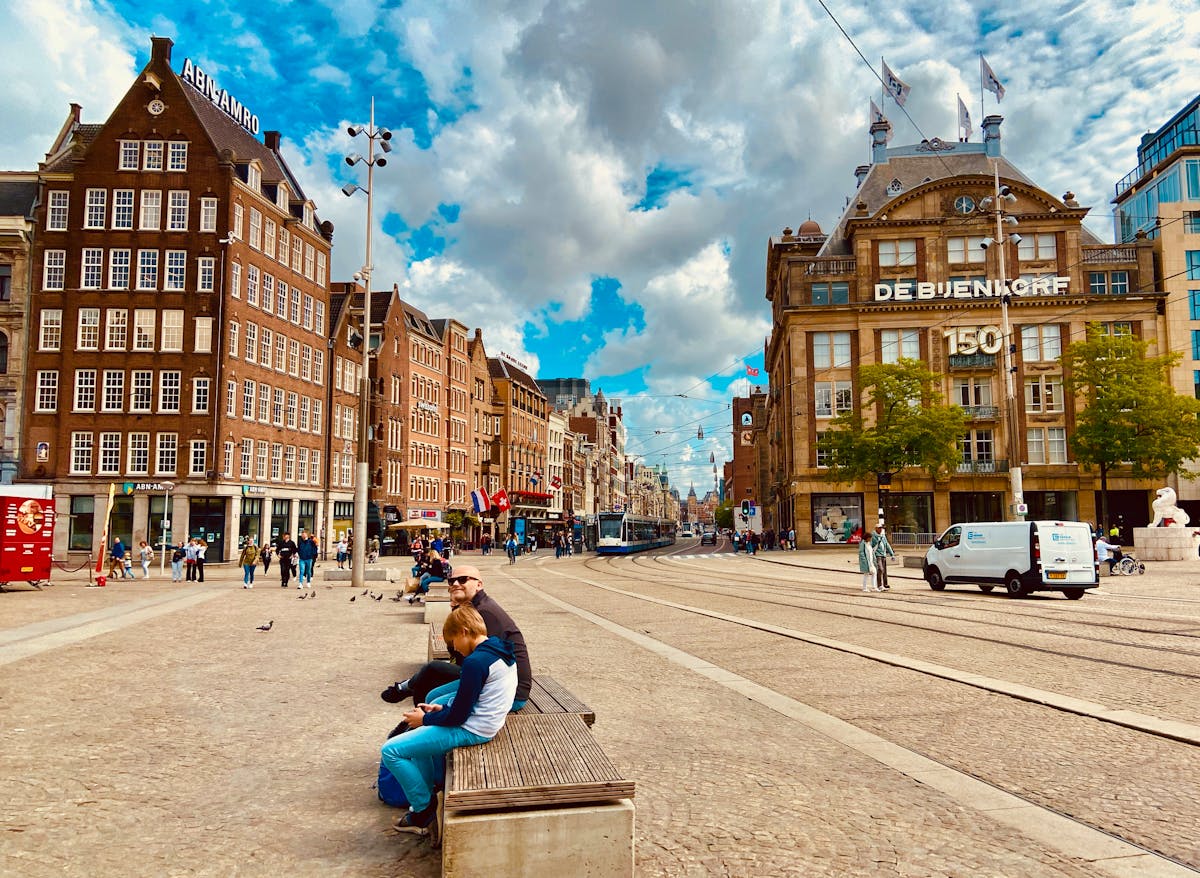 People walking through Dam Square in Amsterdam with the Royal Palace and historic buildings