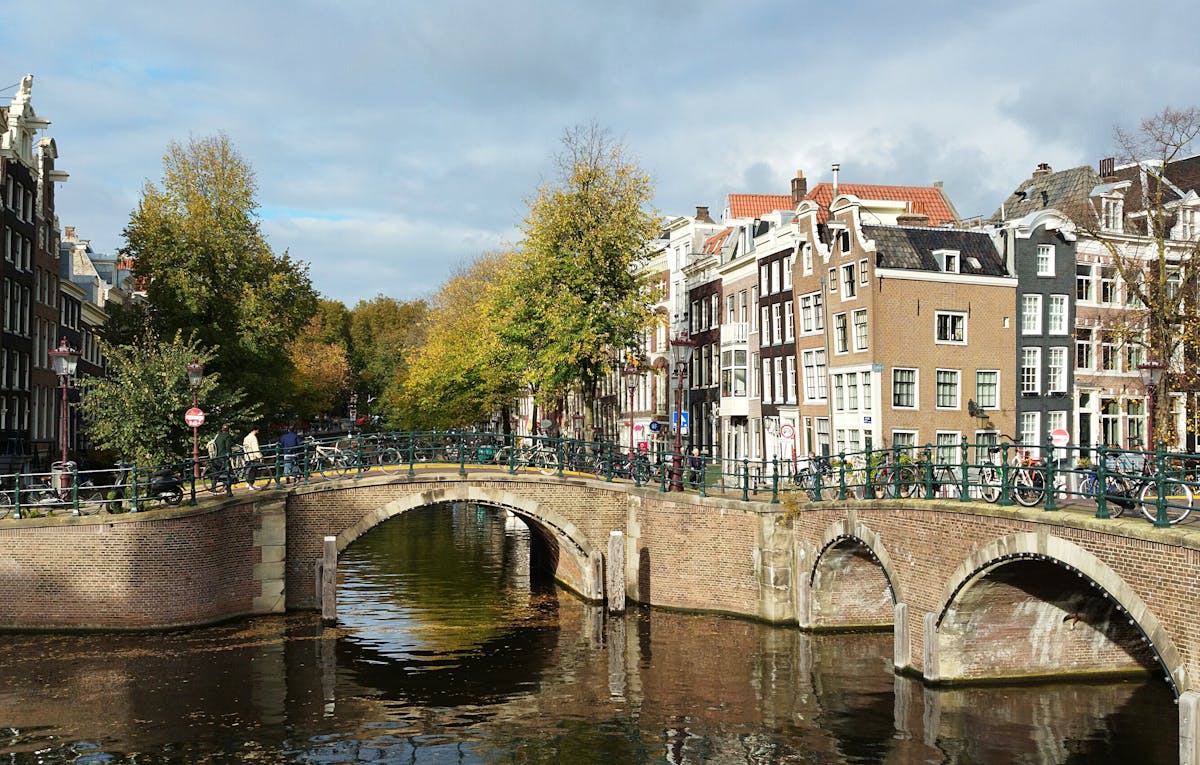 Scenic Amsterdam canal bridge with autumn foliage and historic buildings
