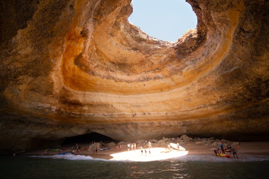 Inside Benagil Cave with sunlight illuminating the sandy beach