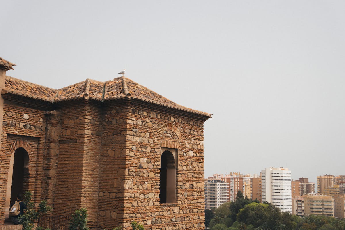 Ancient Alcazaba fortress walls with the modern Malaga cityscape stretching to the Mediterranean behind it