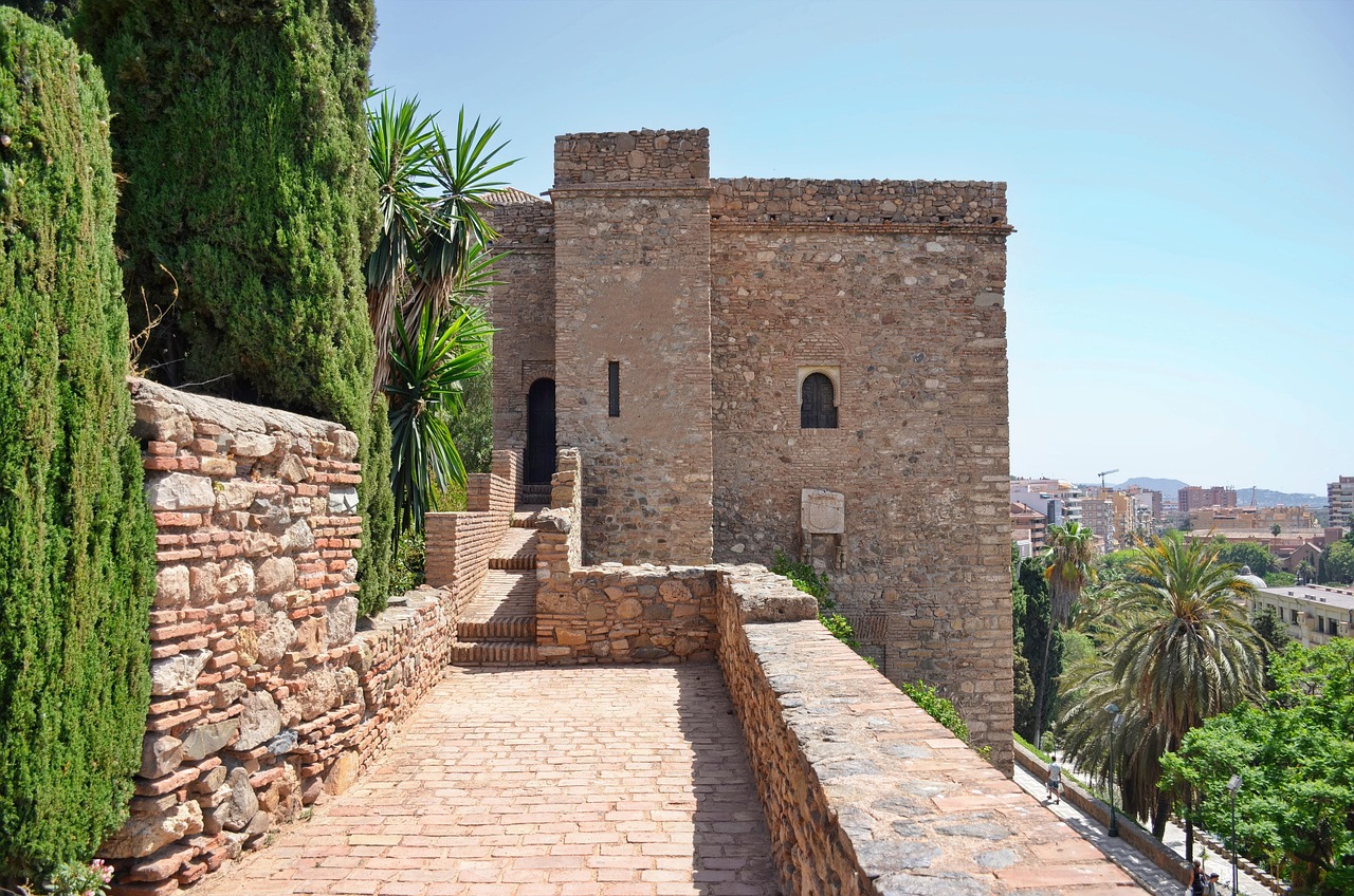 The distinctive red brick fortress walls of the Alcazaba in Malaga rising against a clear blue sky
