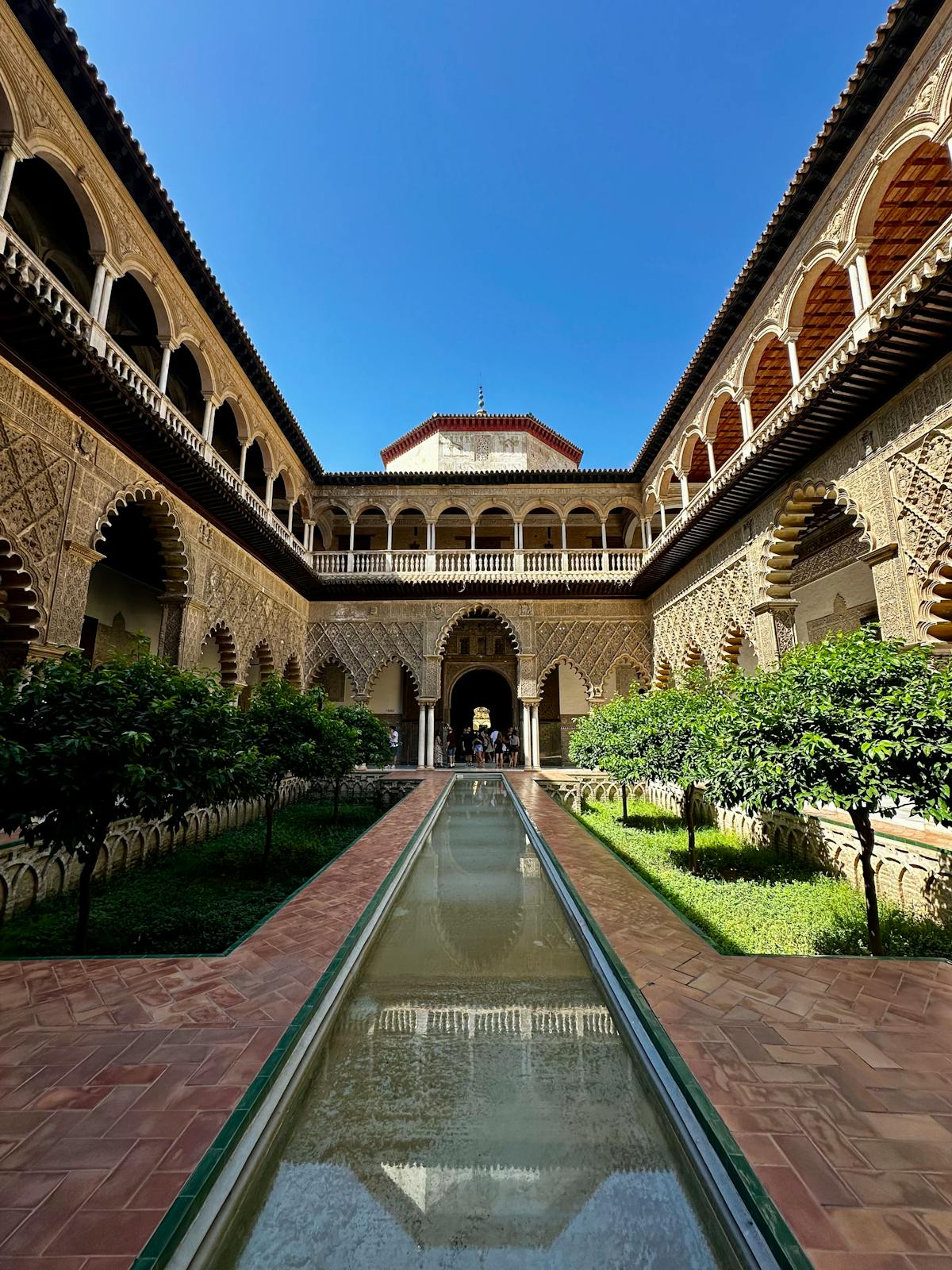 The Alcazar of Seville courtyard with arched walkways and lush gardens