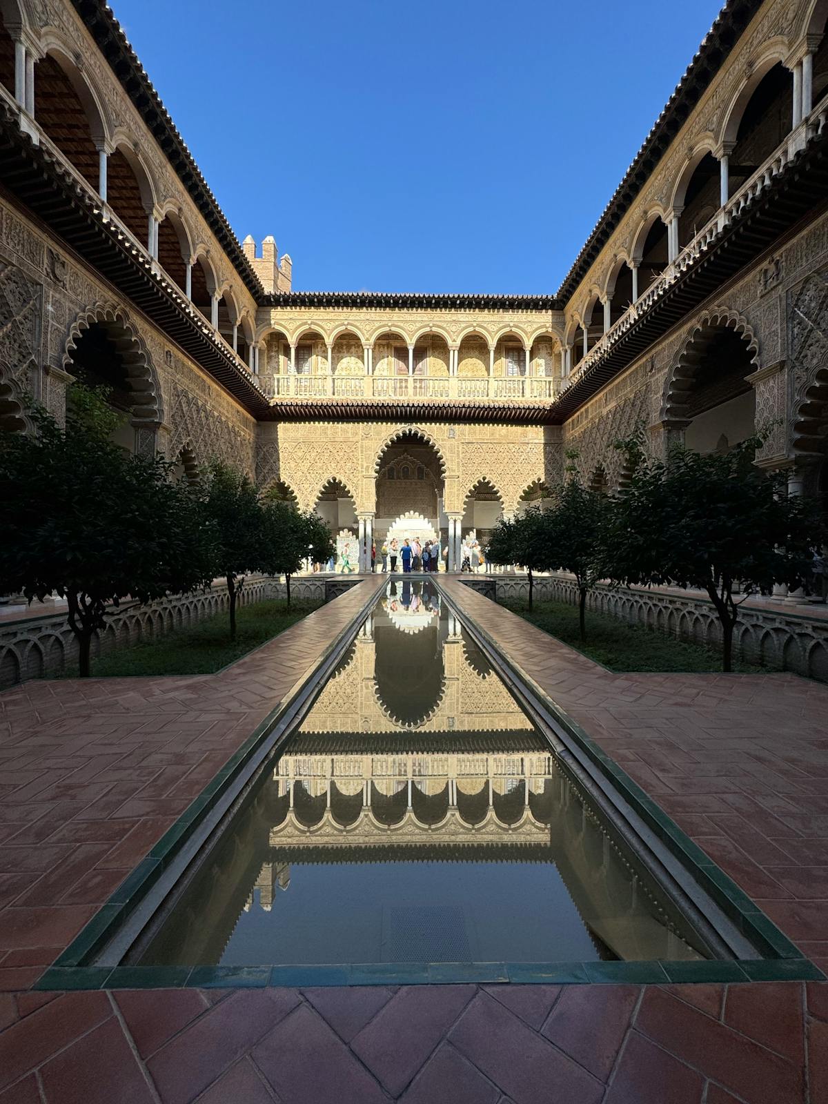 Courtyard of the Royal Alcazar in Seville with a reflective pool and Moorish arches