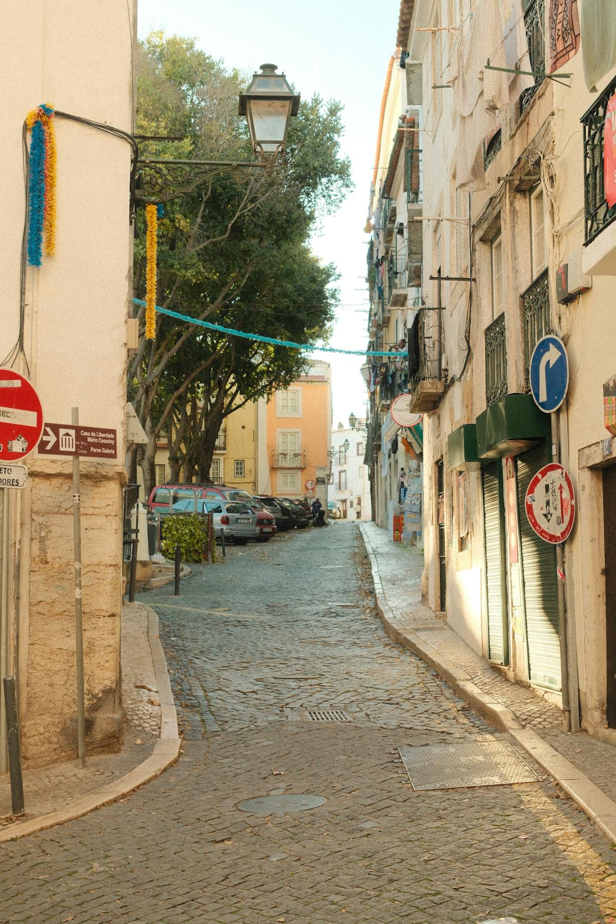 Narrow cobblestone lane in Alfama decorated with festive garlands overhead