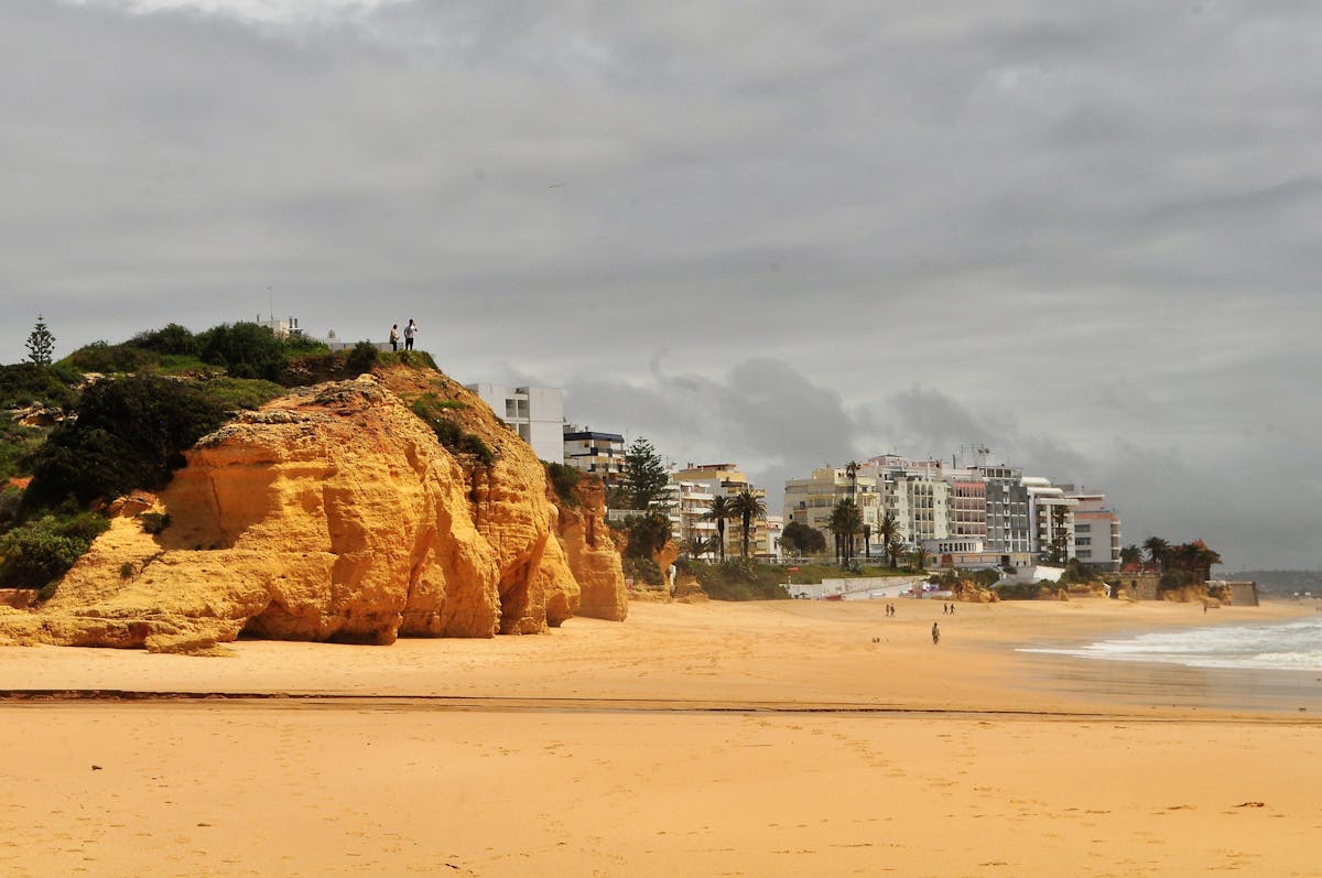 Beautiful Algarve beach scene with golden cliffs and sandy shoreline under a cloudy sky