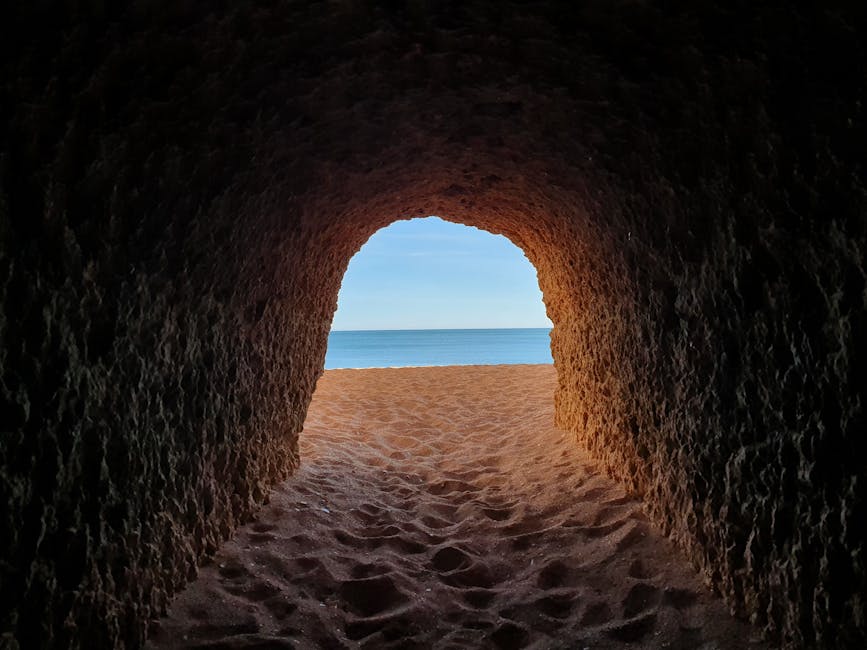 View from inside a cave tunnel out to a sandy beach in the Algarve