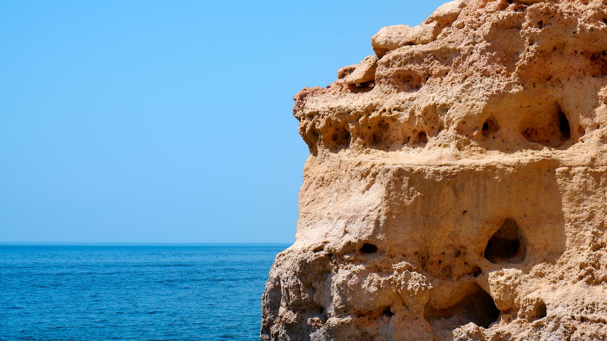 Limestone cliffs dropping into azure Atlantic Ocean water along the Algarve coast of Portugal