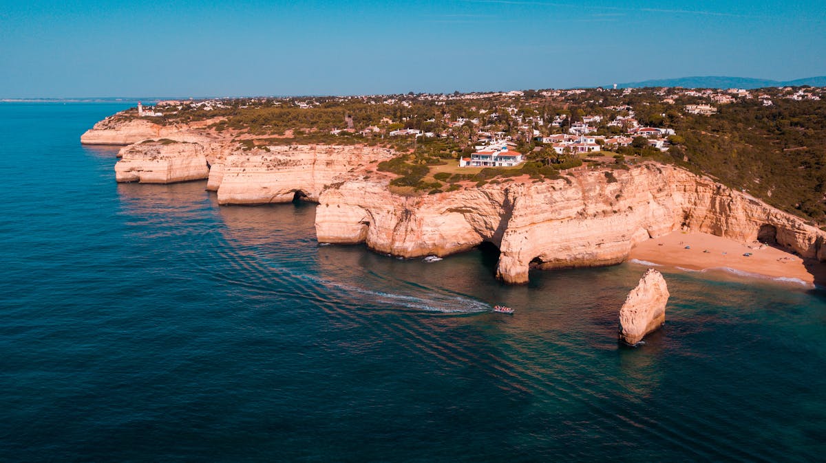 Aerial view of rugged golden cliffs and turquoise Atlantic waters along the Algarve coast