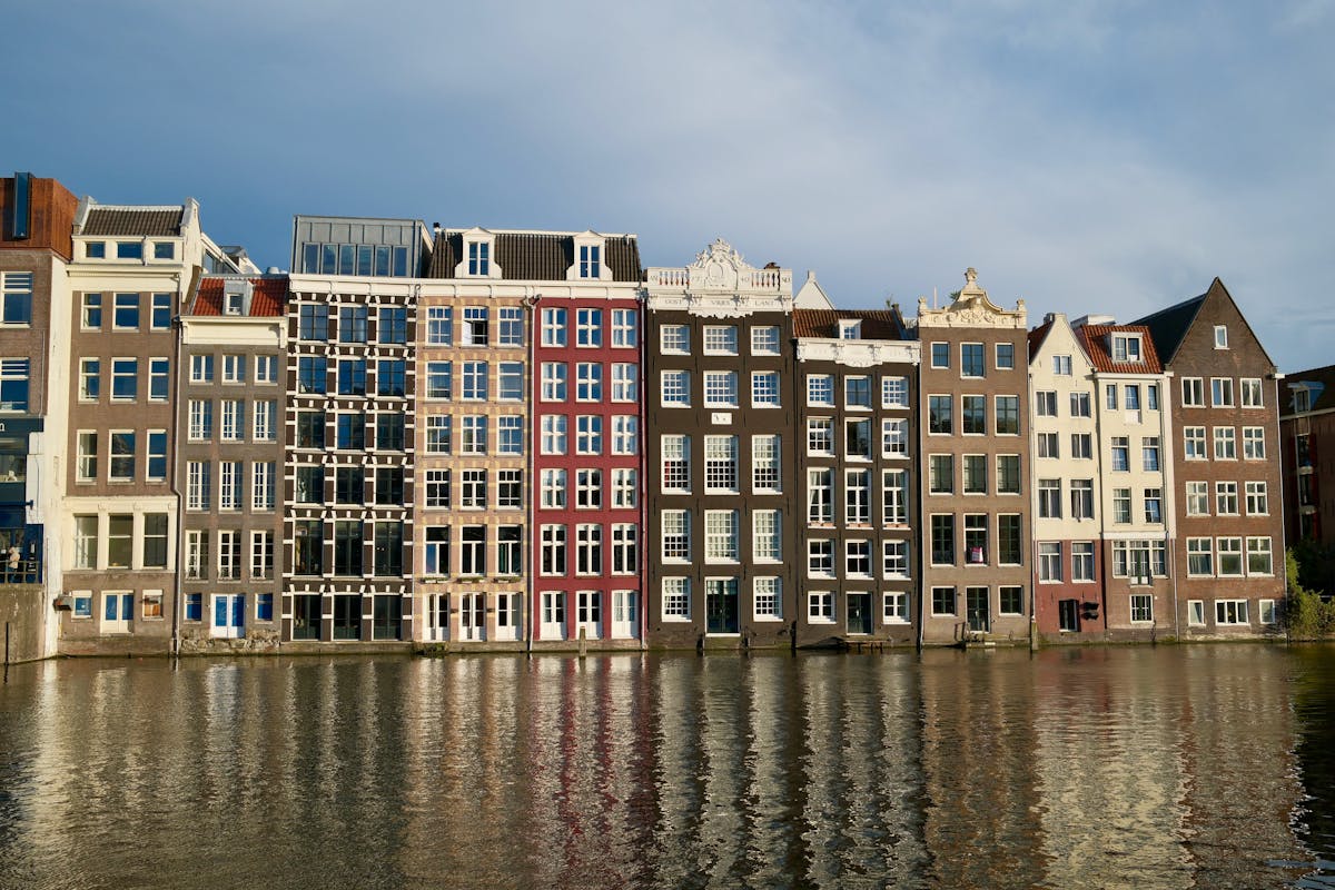 Row of elegant historic Amsterdam canal houses reflected in calm waterway