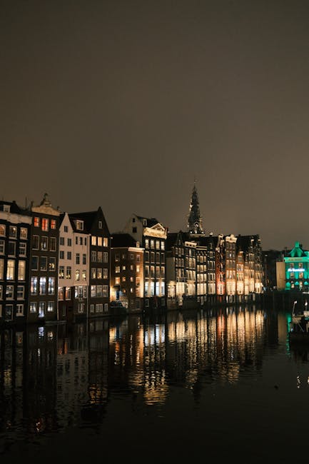 Amsterdam canal bridge lit up at twilight with golden reflections
