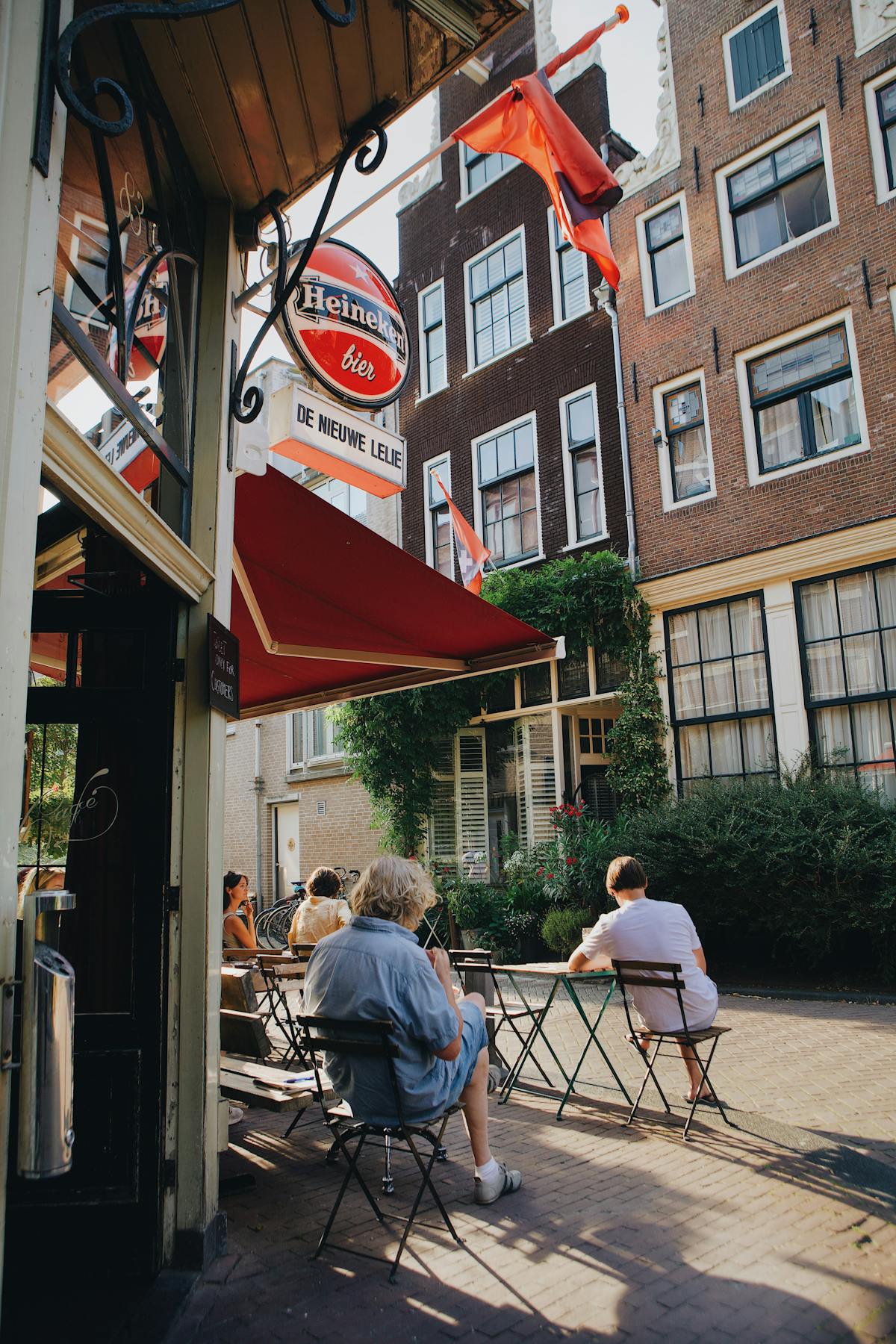 Outdoor cafe in Amsterdam with people enjoying a sunny day among historic buildings