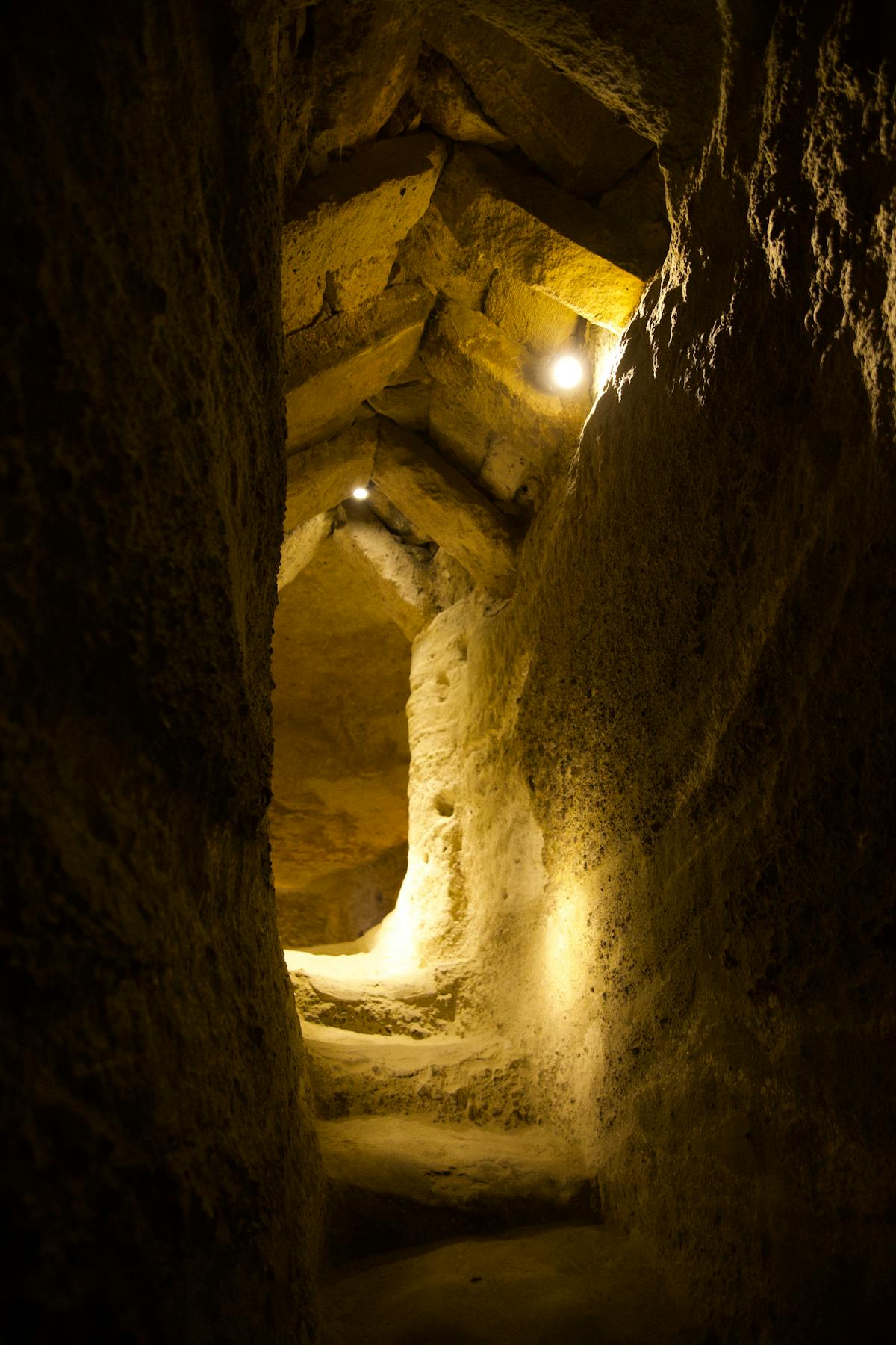 Ancient underground corridor with stone walls illuminated by warm light