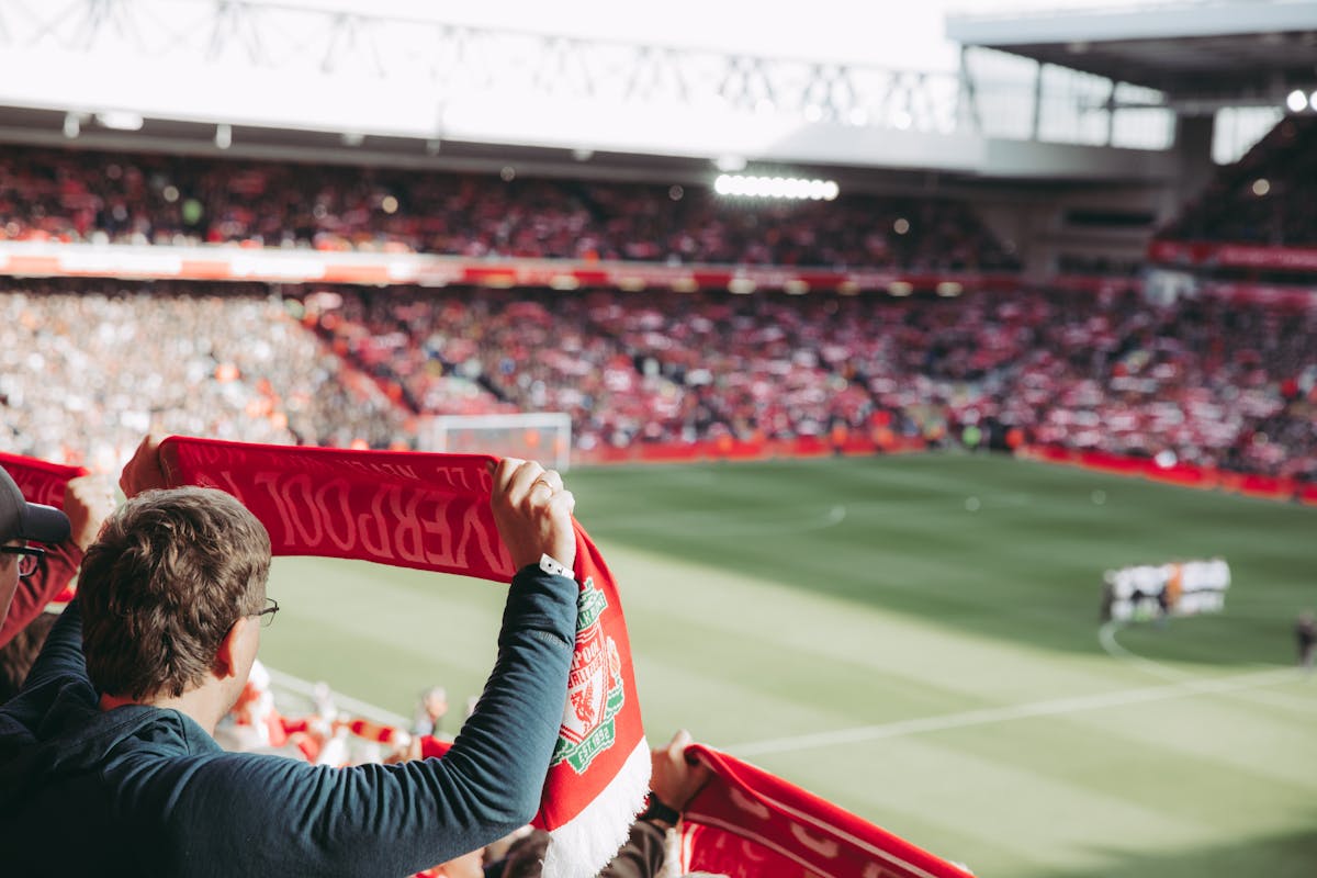 Football supporters holding scarves aloft at Anfield Stadium during a match