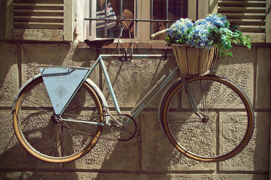Old stone building in downtown Antibes with flowers and bicycle on narrow street
