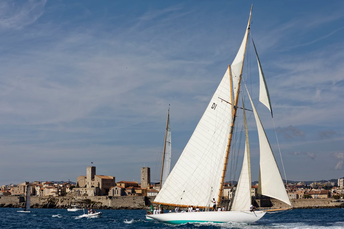 White sailboat sailing past Antibes old town waterfront