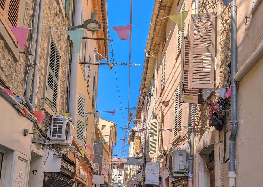 Sunny narrow street in Antibes France with colorful bunting and Mediterranean architecture