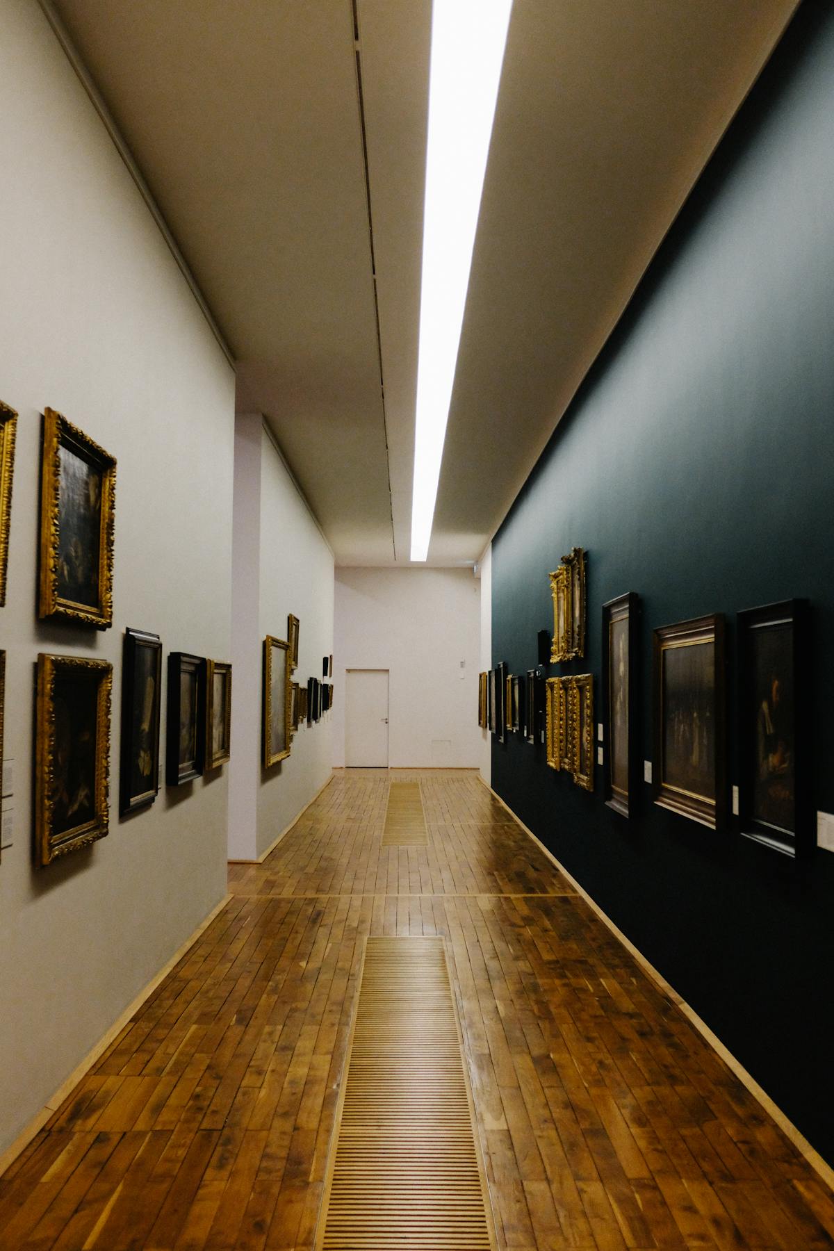 A beautifully lit museum corridor showcasing classic framed paintings on wooden floors