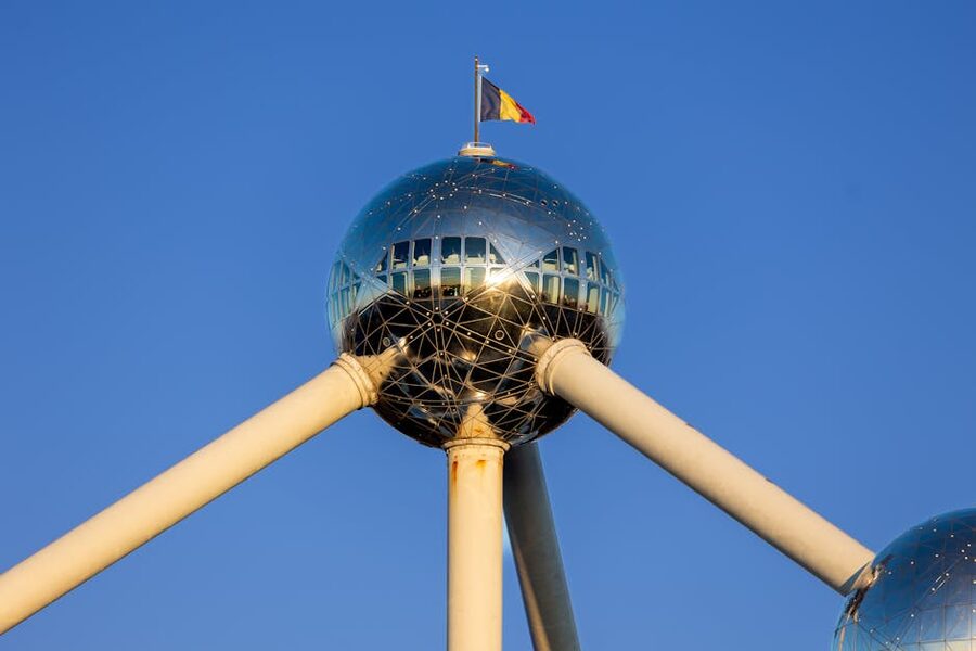 Atomium Brussels with Belgian flag waving against blue sky