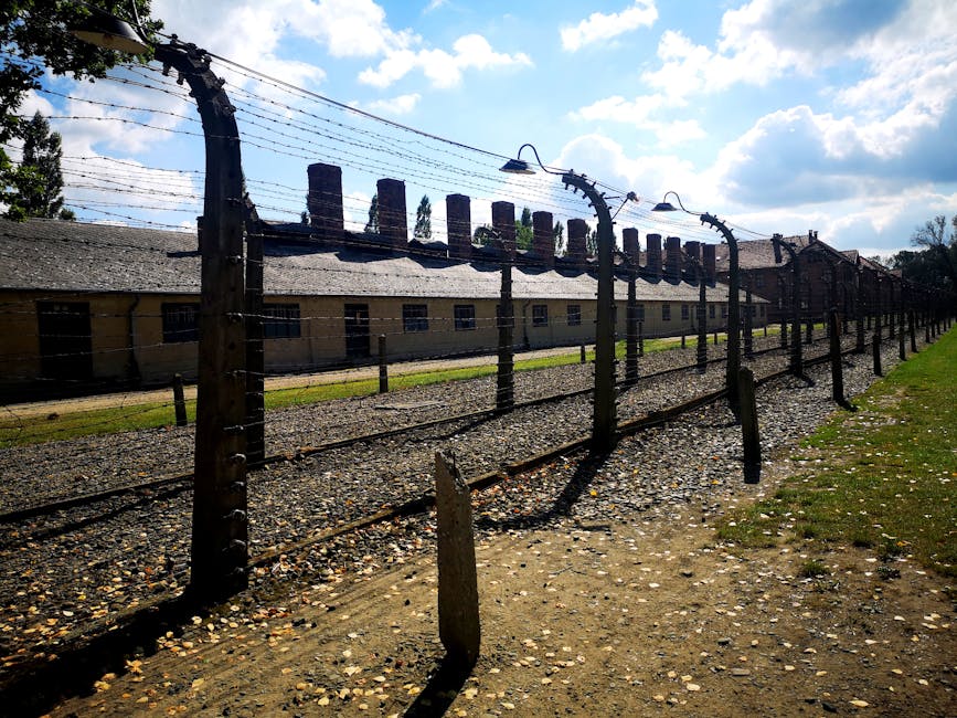 Barbed wire fence at a historical concentration camp with barracks