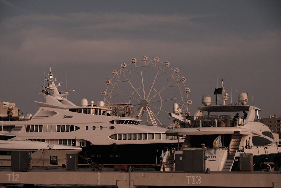 Luxury yachts at Barcelona harbor with Ferris wheel at sunset