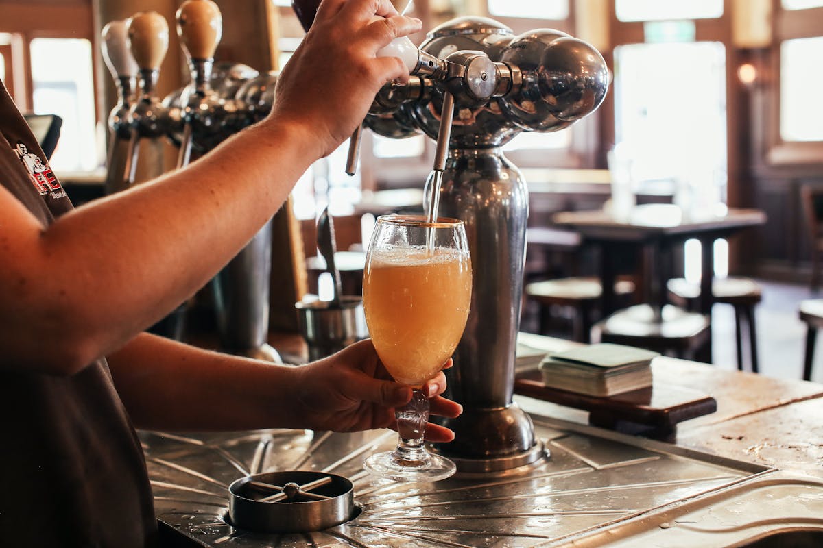 Bartender pouring a fresh draft beer at a bar counter