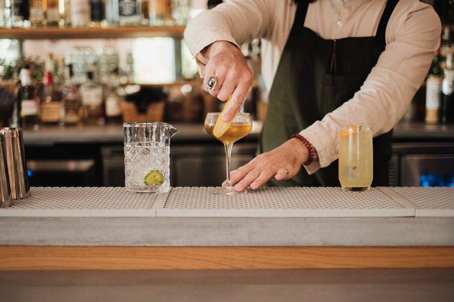 Bartender in apron garnishing cocktails at a bar counter