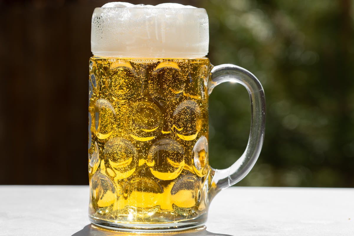 A glass of golden Bavarian lager with a thick foam head served outdoors in Munich