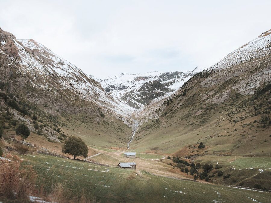 Snow-capped Pyrenees mountains rising above green valley in Andorra