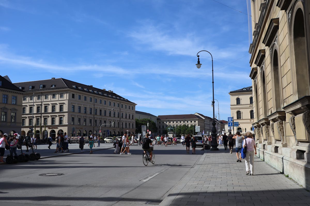 Odeonsplatz in Munich with people walking and cycling under a clear blue sky