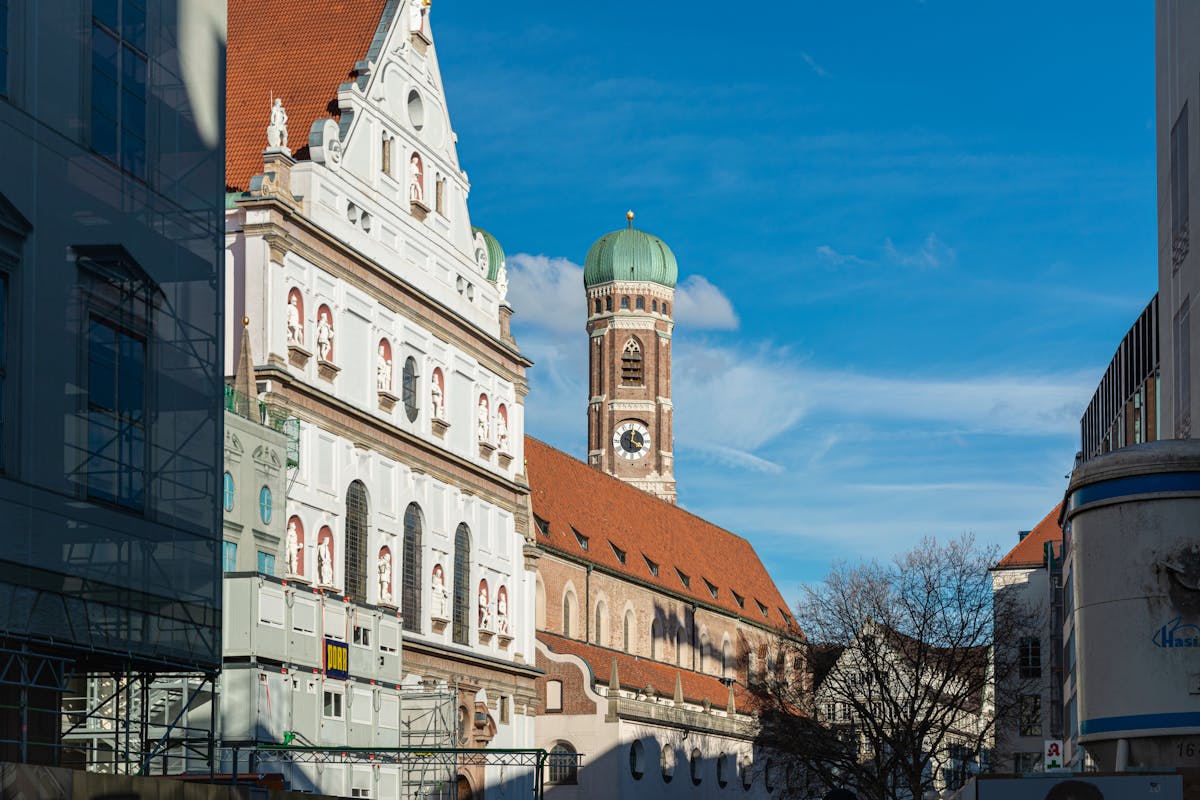 Facade of St Michaels Church and tower of the Frauenkirche in Munich under clear blue sky