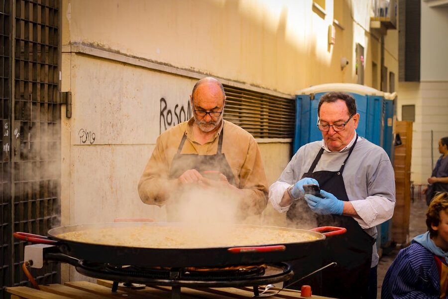 Two chefs cook a large paella outdoors in Spain