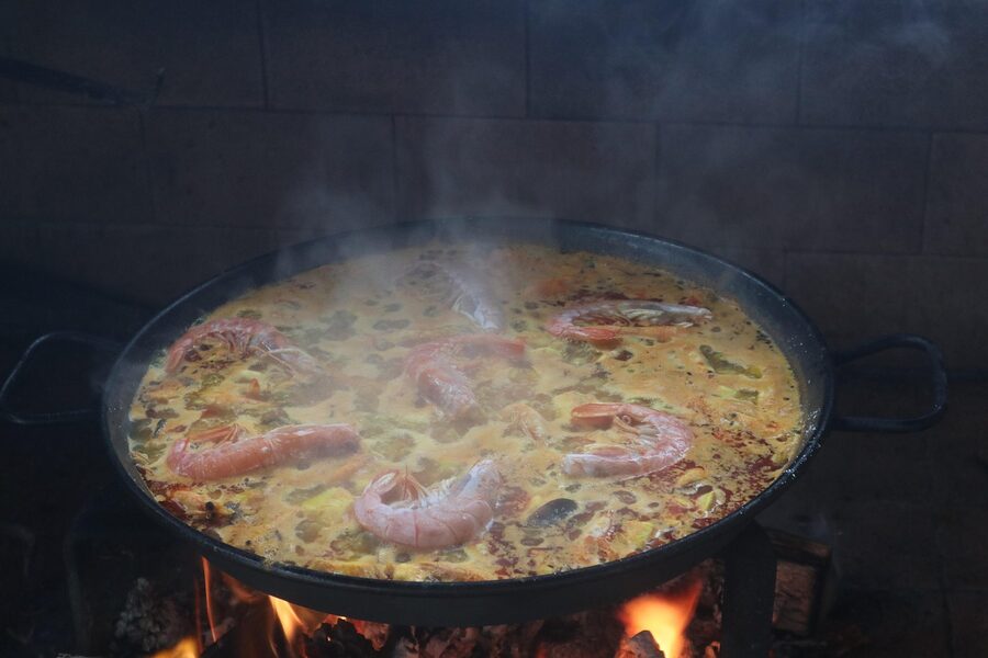 Paella and fideua pans cooking over an open flame in Valencia, Spain