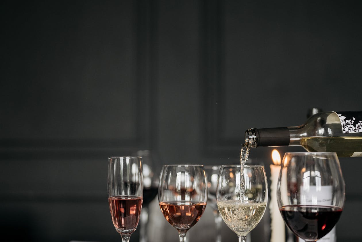 Three wine glasses containing red white and rose wine arranged on a dark table
