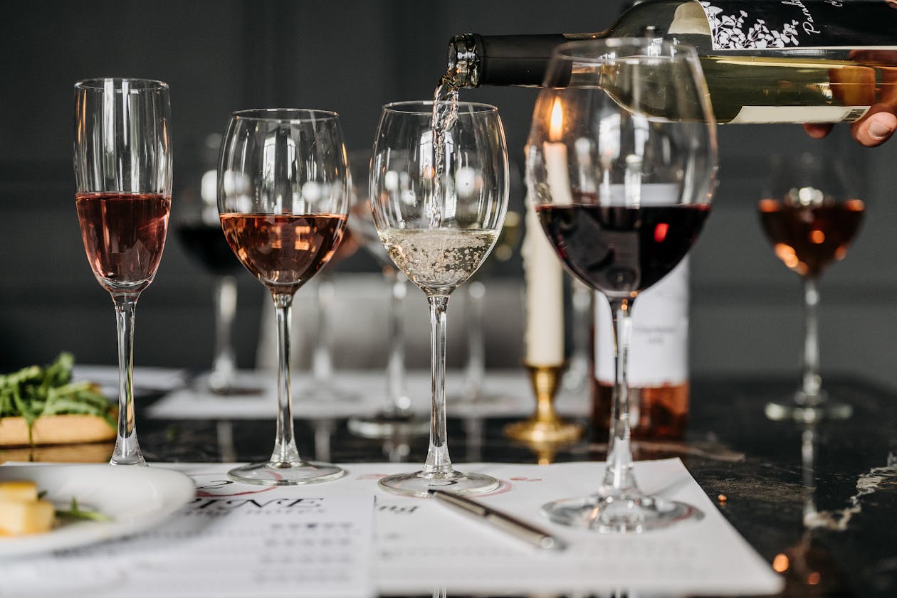 An elegant wine tasting setup with multiple wines being poured into glasses on a table