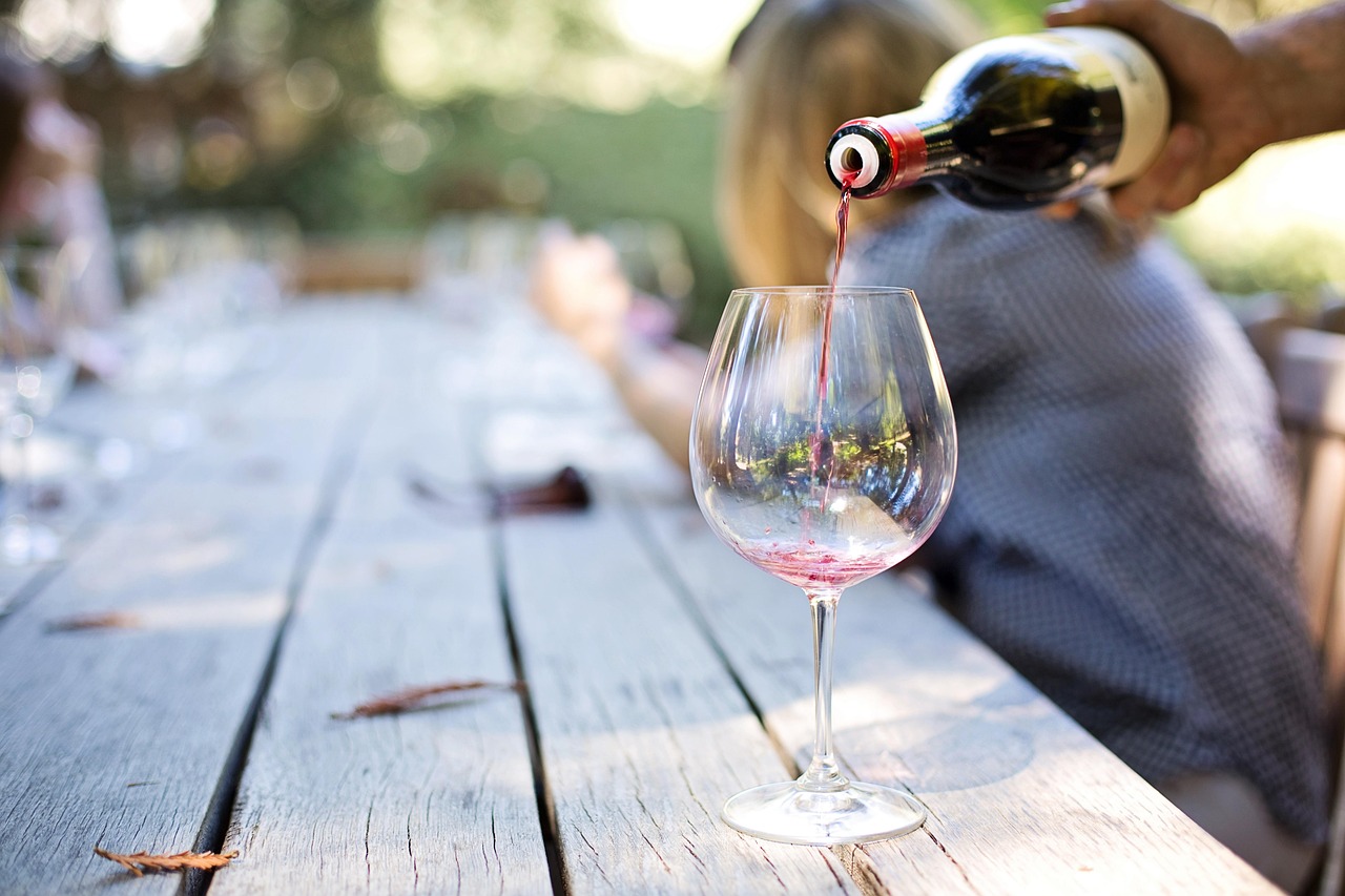 Close-up of red wine being poured into a glass with warm lighting