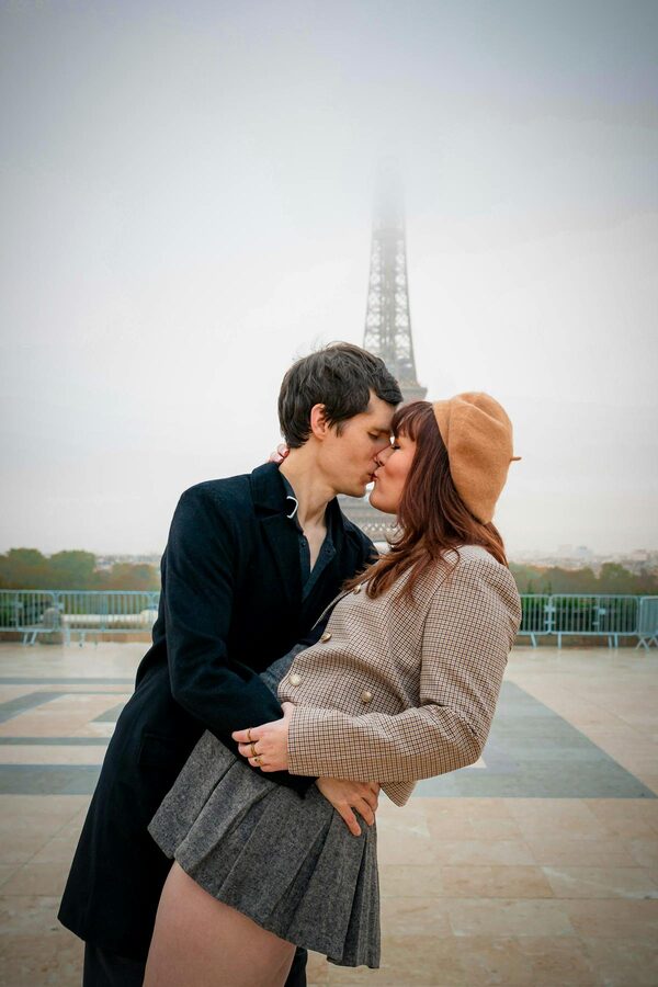 A couple posing for a photoshoot with the Eiffel Tower in the background in Paris