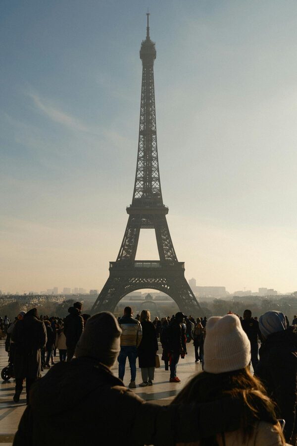 A person walking near the Eiffel Tower on an autumn day with fallen leaves