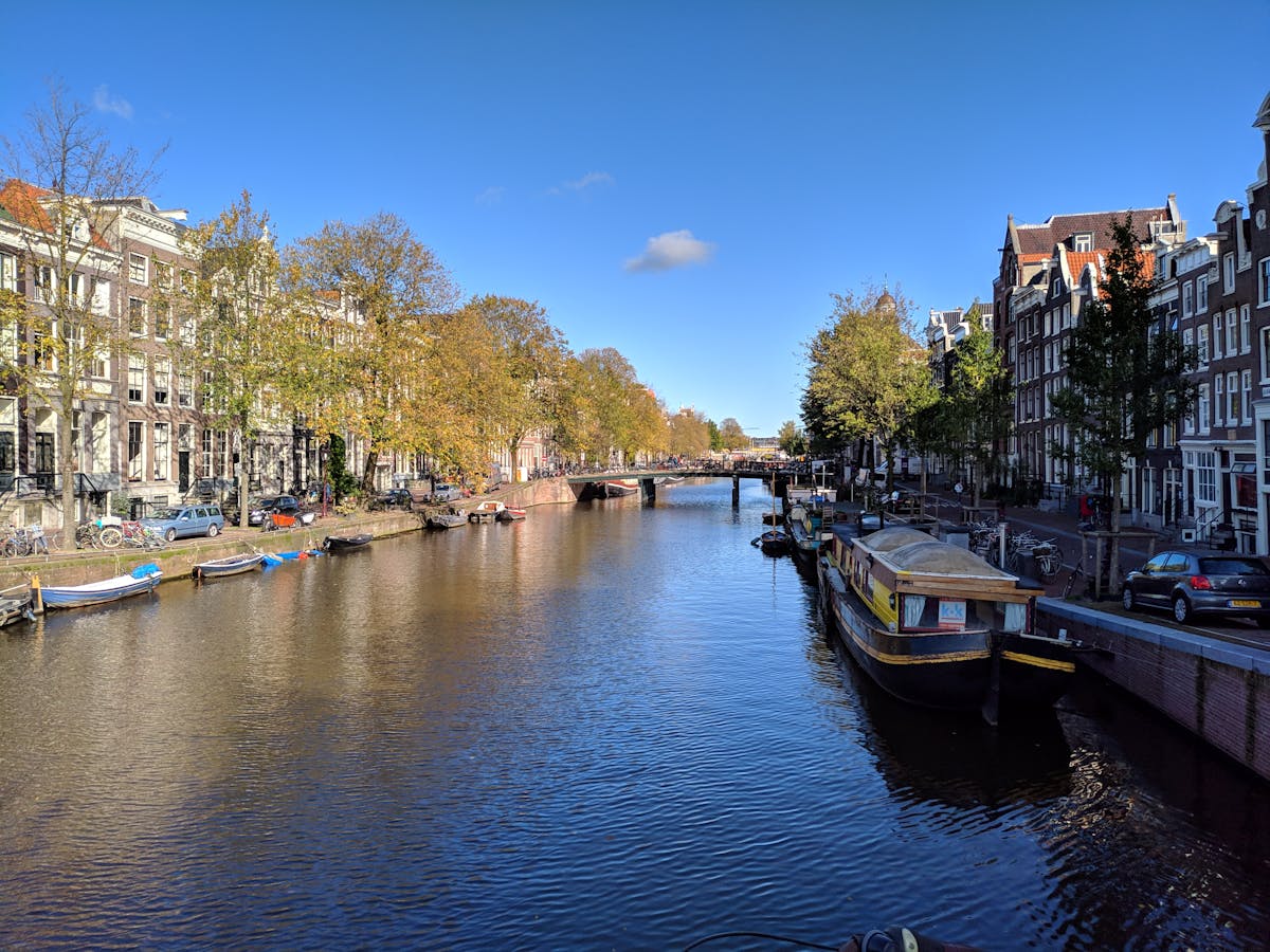 Amsterdam canal with historic houses under blue sky in autumn