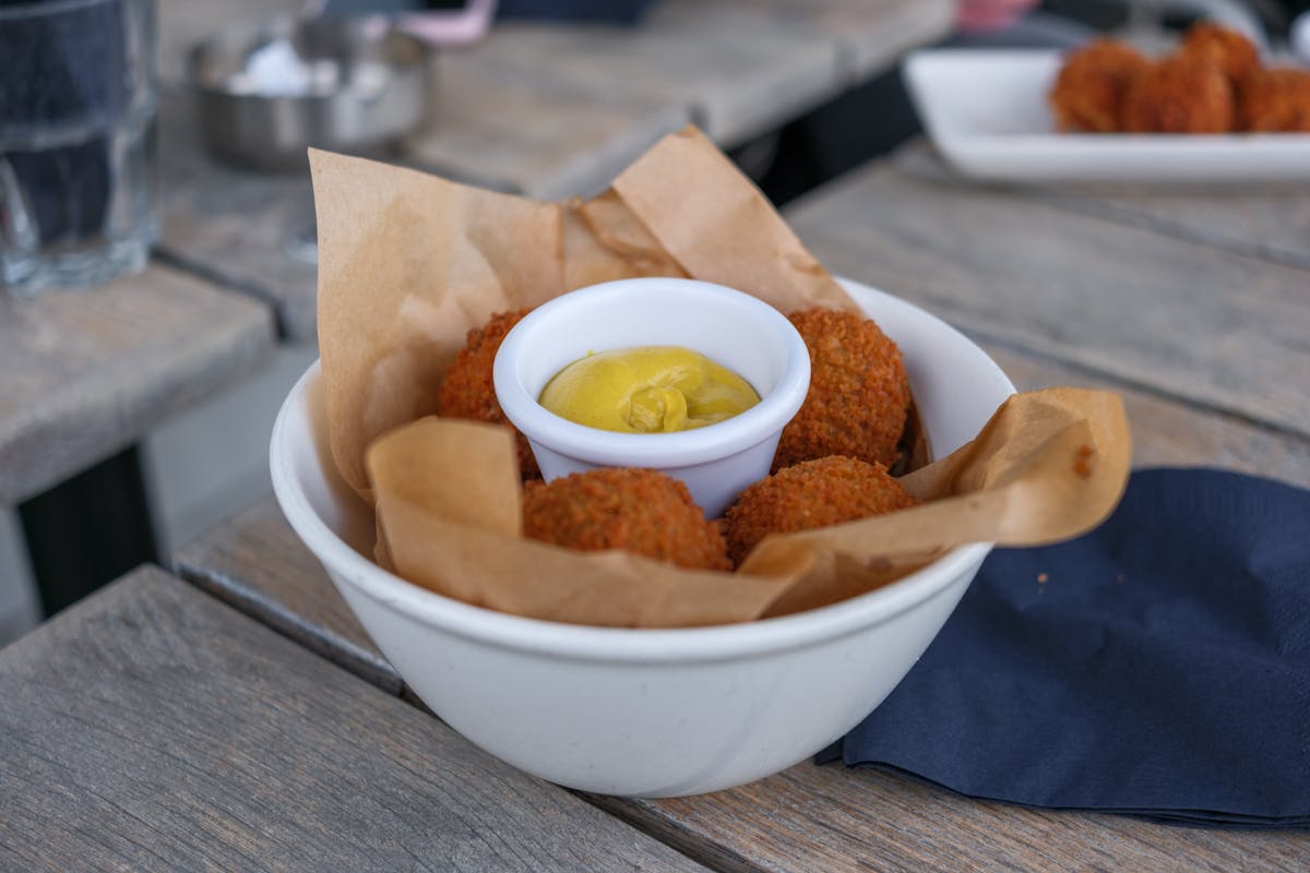 Bowl of crispy bitterballen served with mustard in a cozy cafe