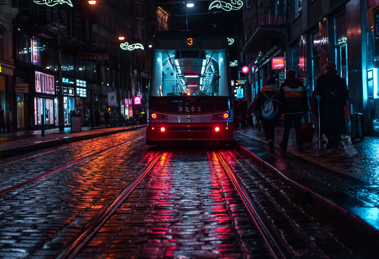 Tram on cobblestone street in Prague reflecting city lights on a rainy evening