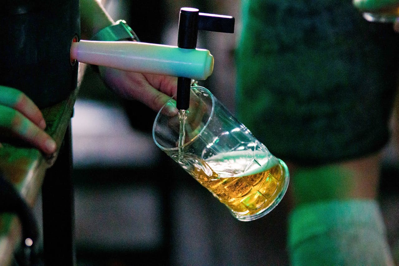 Person pouring beer from a tap into a glass at a bar