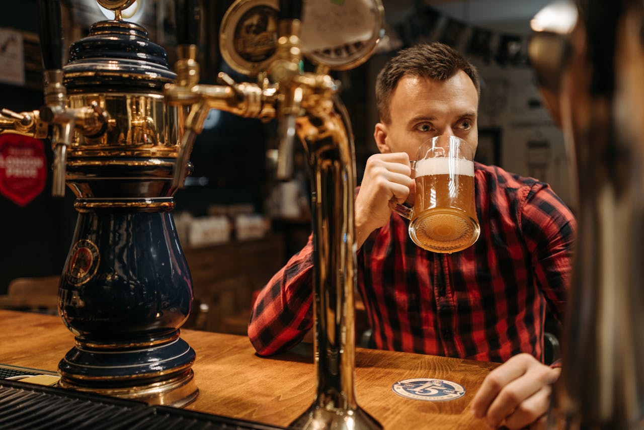 Man sipping beer from a mug at a pub with vintage beer taps