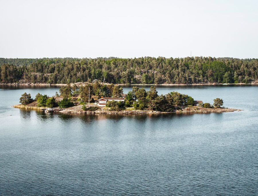 A red cottage surrounded by calm water on a small island in the Stockholm Archipelago