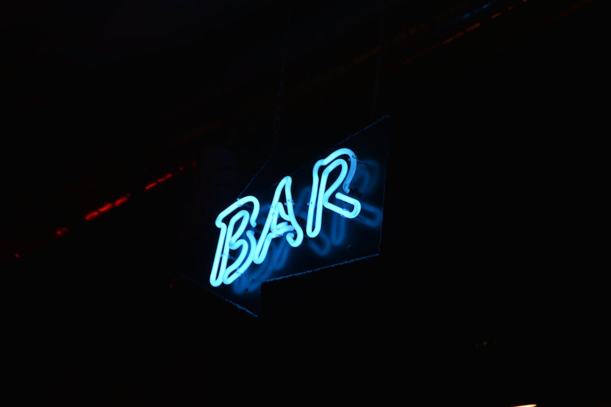Blue neon bar sign glowing against a dark background