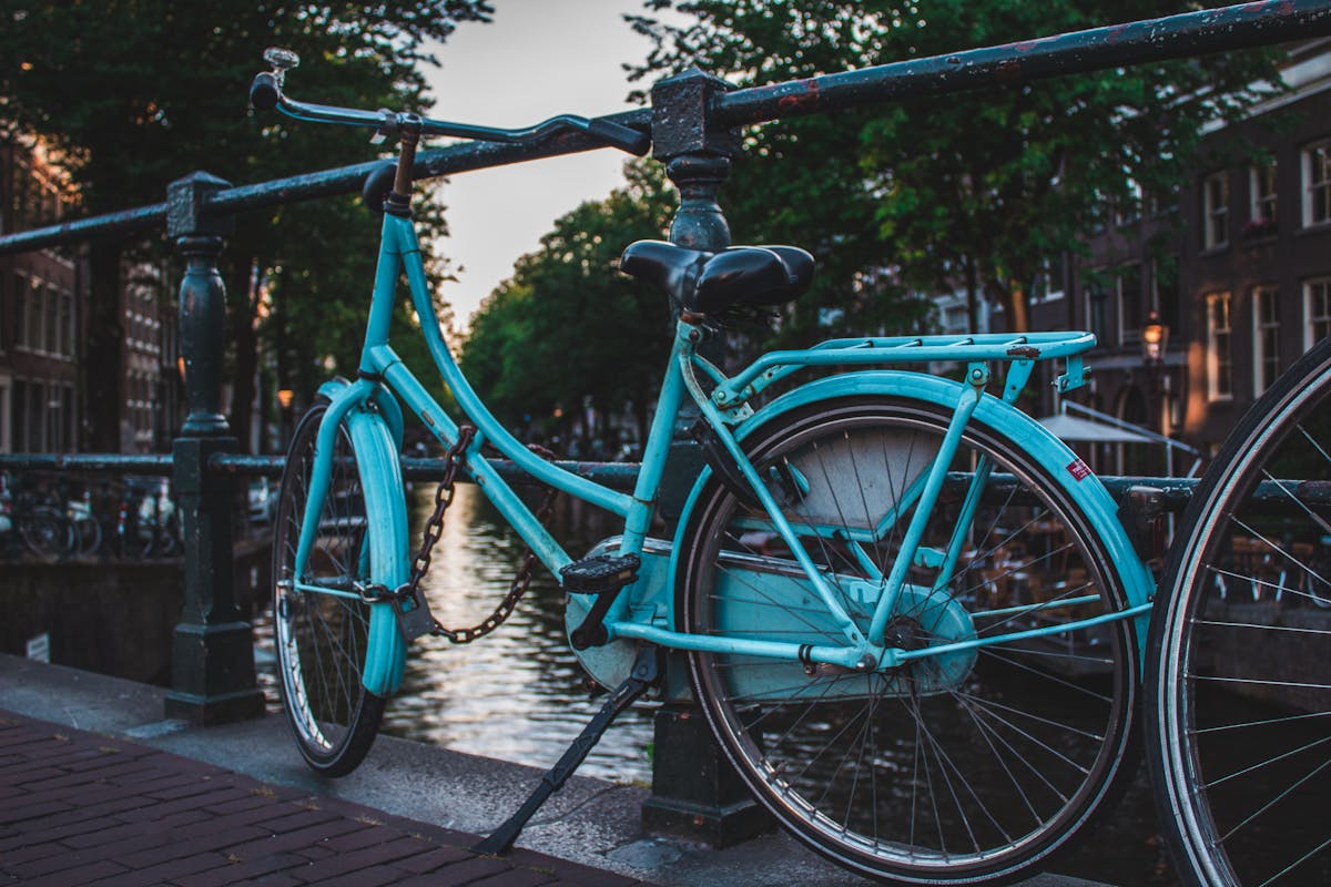 A blue bicycle parked on a canal bridge in Amsterdam