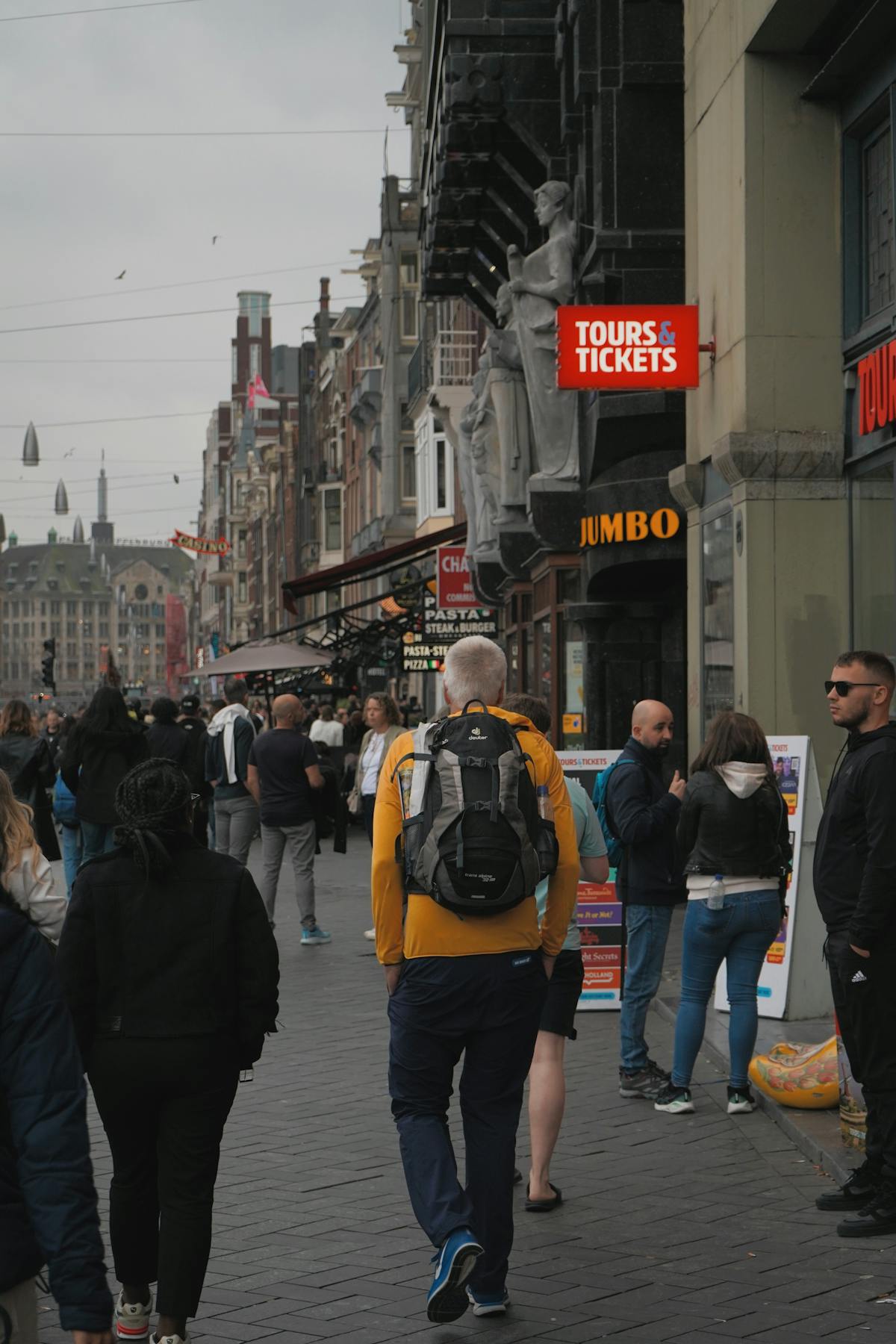 A bustling street in Amsterdam with travelers, shops, and architecture
