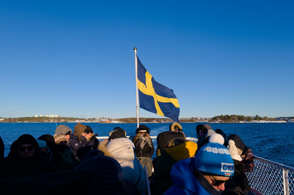 People on a winter boat tour in Stockholm with the Swedish flag waving
