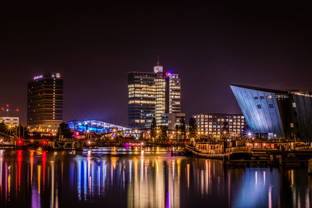 Reflective night view of Amsterdam modern skyline by the water