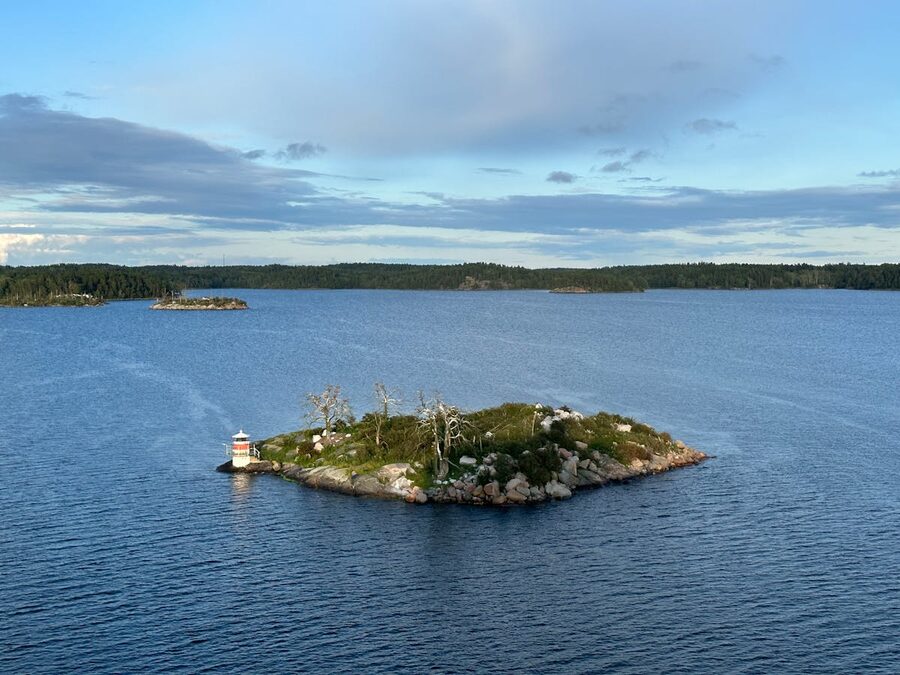 A small island with a lighthouse in a vast archipelago setting