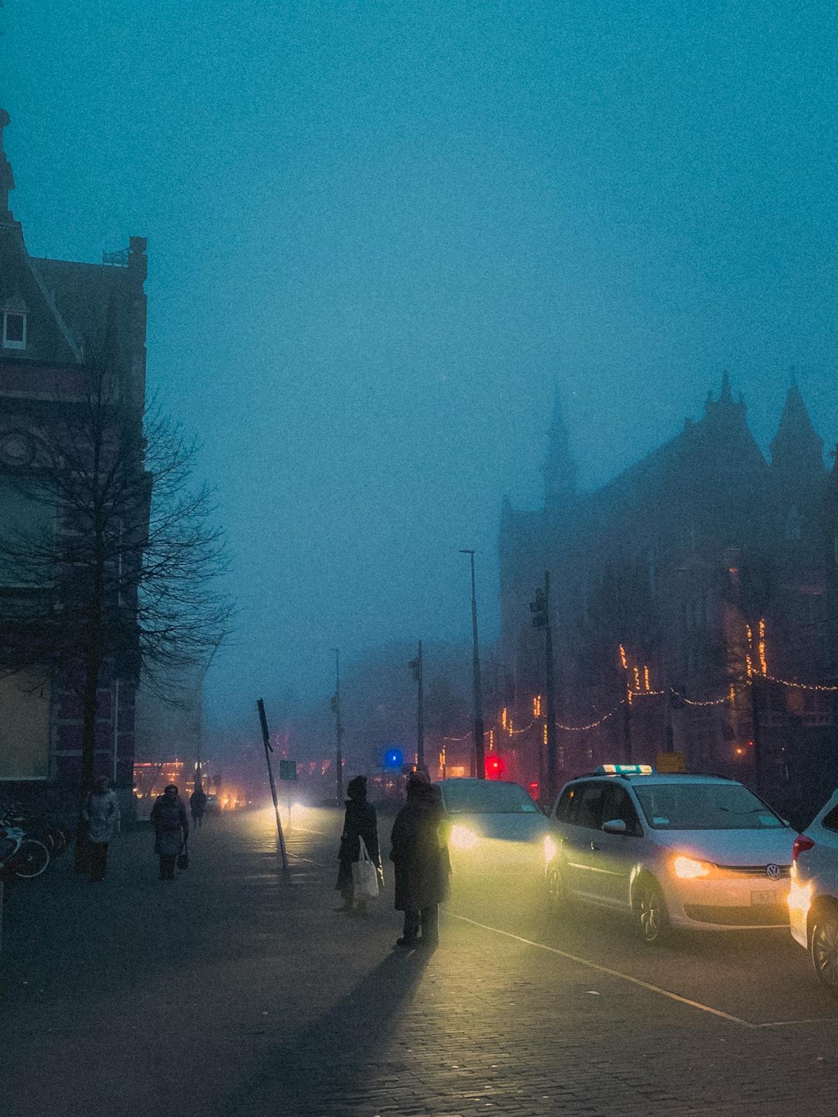 Foggy Amsterdam streets at night with warm lights